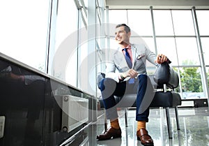 Low angle shot of a handsome young businessman in a stylish modern office space with large windows.