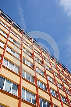 Low angle shot of a high orange apartment building under a clear blue sky