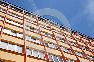 Low angle shot of a high orange apartment building under a clear blue sky