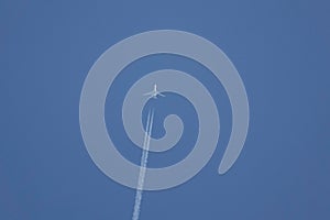 Low angle shot of a jet plane with contrails against a clear blue sky