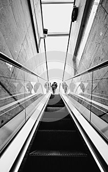 Low angle shot of a man stepping off a grey metal escalator in a modern building photo