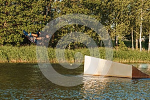 Low angle shot of man wakeboarding on a lake. Man water skiing at sunset.