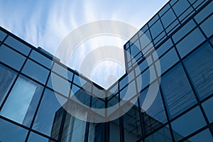 Low angle shot of a modern glass building under the blue cloudy sky