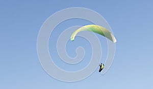 Low angle shot of a person parachuting on a blue sky background