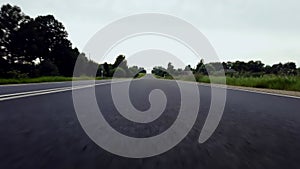 A low angle shot of a road and green hills with blue skies and clouds. Road in perspective