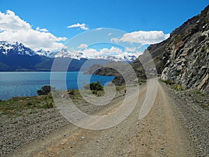 Low angle shot of a road, hills, a river, and snowy mountains