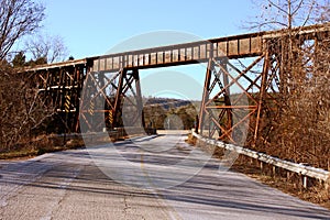 Low angle shot of a rusty railroad bridge surrounded by leafless trees