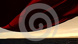 Low angle shot of sails blowing in stormy wind on waterfront at sunset