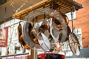 Low angle shot of shiny steel pots and pans hanging from a rack in a shop ceiling