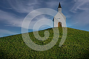 Low angle shot of a small church on a rural green hill in the Netherlands