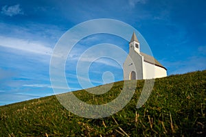 Low angle shot of a small church on a rural green hill in the Netherlands