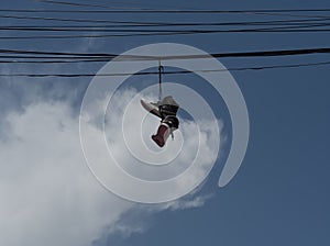 Low angle shot the sneakers hanging from electrical wire against a blue sky with clouds