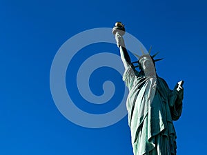 Low-angle shot of the Statue of Liberty against the clear blue sky with a copy space on the left