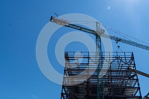 Low angle shot of a steel building structure and a crane in a blue sky