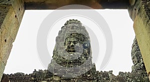 Low angle shot of stone face tower framed by a doorway at bayon temple