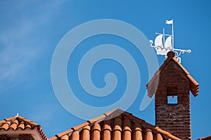 Low angle shot of a terracotta roof with a beautiful white boat weathervane decoration