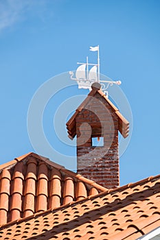 Low angle shot of a terracotta roof with a beautiful white boat weathervane decoration