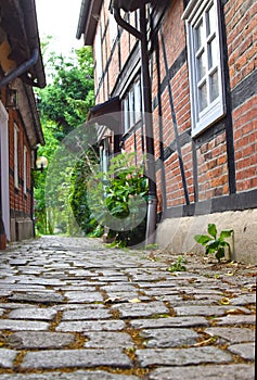 Low angle shot to a historical cobblestone alley with red half-timbered houses