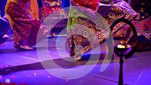 Low angle shot of unidentified girls legs in traditional ghagra dress dancing to Indian classical music in front of a diya or