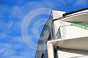 Low angle shot of a white apartment with a balcony under a blue sky