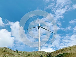 Low angle shot of a windmill on hill under sunlight and blue sky at daytime - environmental concept