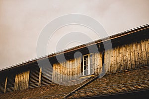 Low angle shot of a wooden house with a white window on the 2nd floor