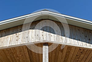 Low angle shot of a wooden roof overhangs against a blue sky