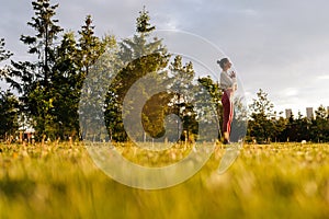 Low-angle side view of calm young woman with closed eyes holding hands in namaste gesture standing on yoga mat relaxing