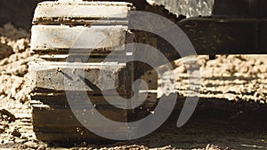 A low angle of a small backhoe digging a drainage ditch. Earth moving equipment