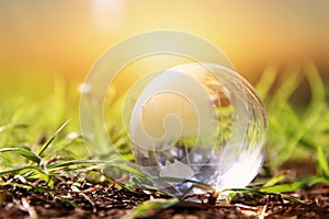 low angle small crystal globe in the grass. travel and global issues concept.
