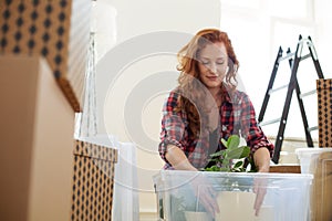 Low angle on smiling woman packing a plant into a box during rel
