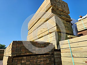 Low angle of a stack of lumber with a clear blue sky above