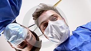 Low angle surgeons looking at a patient after a succesful operation and shake hands