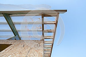 Low angle top view eaves of new wooden roof with reliable supports and windproof membrane against blue sky