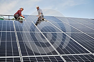 Male workers installing solar panel on metal construction.