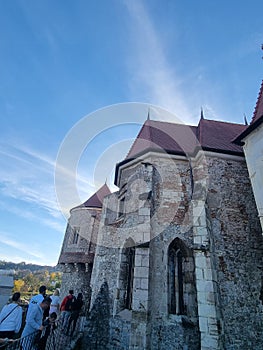 Low-angle vertial shot of the Poenari Citadel and people beside it in Romania under the blue sky