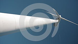 Low angle vertical footage of rotor hub and nacelle of a wind mill with part of their towers.