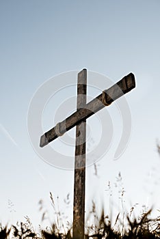 Low angle vertical shot of a handmade wooden cross with a blue sky in the background