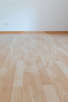 Low angle vertical view of new wooden parquet flooring in a bright light and white apartment room