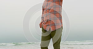 Low angle view of active senior African American man with hand in pocket walking on the beach 4k