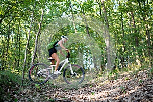 Low angle view of active senior woman biker cycling outdoors in forest.