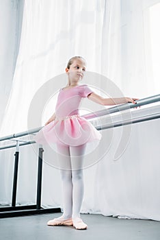 low angle view of adorable little ballerina in pink tutu practicing in ballet