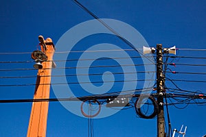 Low angle view against blue sky on isolated high voltage power poles with electric wires, distribution transformer and