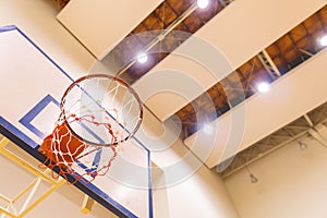 Low angle view of Basketball hoop in Gym with ceiling spotlight, Sport arena background with copy space