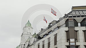 Low angle view of a beautiful building with waving flags on its roof. Action. Concept of classic architecture.