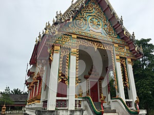 Low angle view of a beautifully decorated Buddist Temple surrounded by trees on a gloomy day