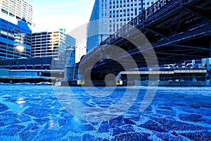 Low-angle view of bridge crossing a frozen Chicago River on a blue, frigid morning in winter.