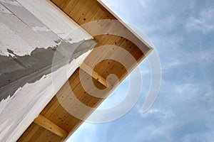 Low angle view of a building fasade under construction unfinished wall and wooden roof boards