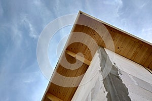 Low angle view of a building fasade under construction unfinished wall and wooden roof boards