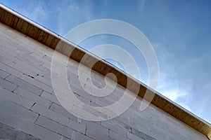 Low angle view of a building fasade under construction unfinished wall and wooden roof boards